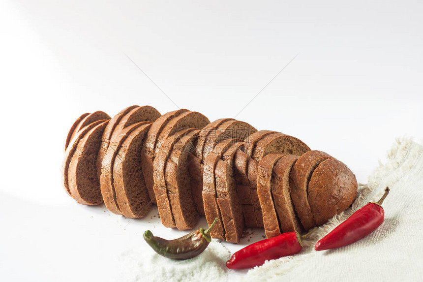 黑麦面包用红辣椒和盐在孤立的白色背景上用各种谷物面粉制成的切碎的烘焙产品一条切成片的面包图片