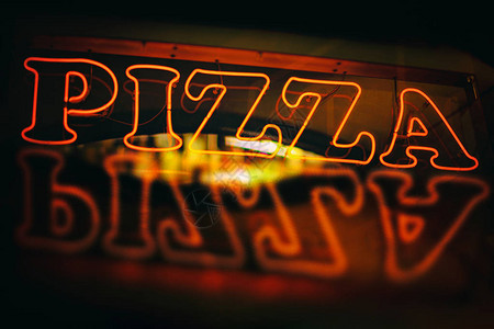 红色霓虹披萨标志在夜间反射背景图片