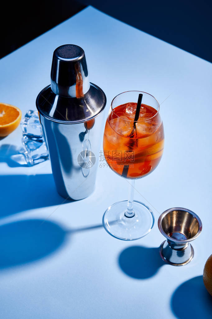 鸡尾酒AperolSpritz橙摇晃器冰块和蓝色底量杯图片