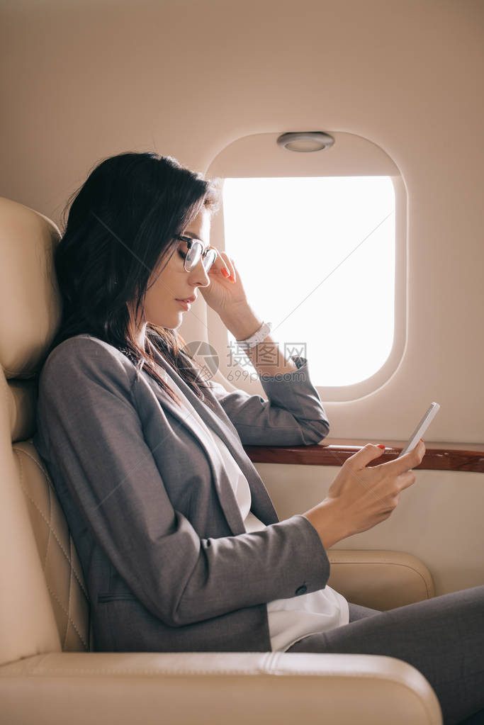 在私人飞机上使用智能手机戴眼镜的图片