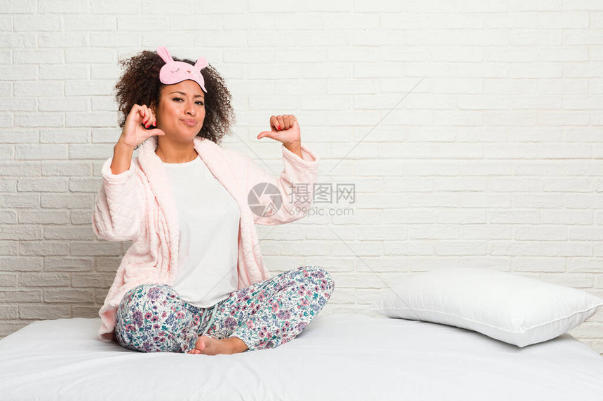 穿着皮雅玛穿衣躺在床上的年轻非洲女感到自豪和自信图片