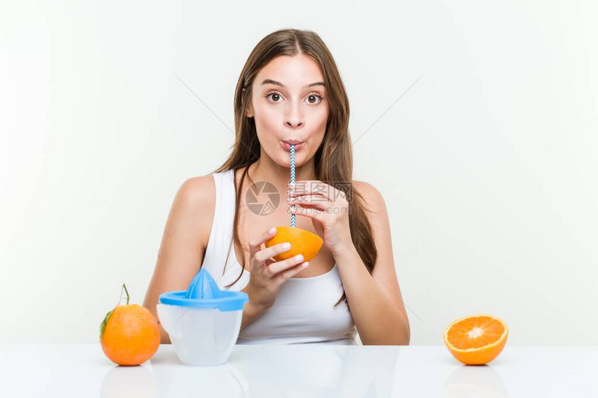 年轻的天主教女青年喝橙子和吸管健图片