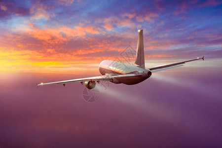 客机在日落的光线下飞越云层图片