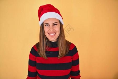 黄色背景下圣诞节时穿着条纹毛衣和圣诞老人帽的年轻美图片