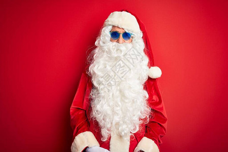 穿着圣诞老人服装和太阳镜的中年男子在孤立的红色背景上身着红墨镜图片