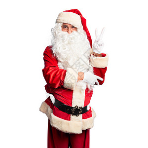 中年帅哥穿圣诞老人服装长着胡子笑着面朝摄影机眨眼的笑脸用手指做胜图片