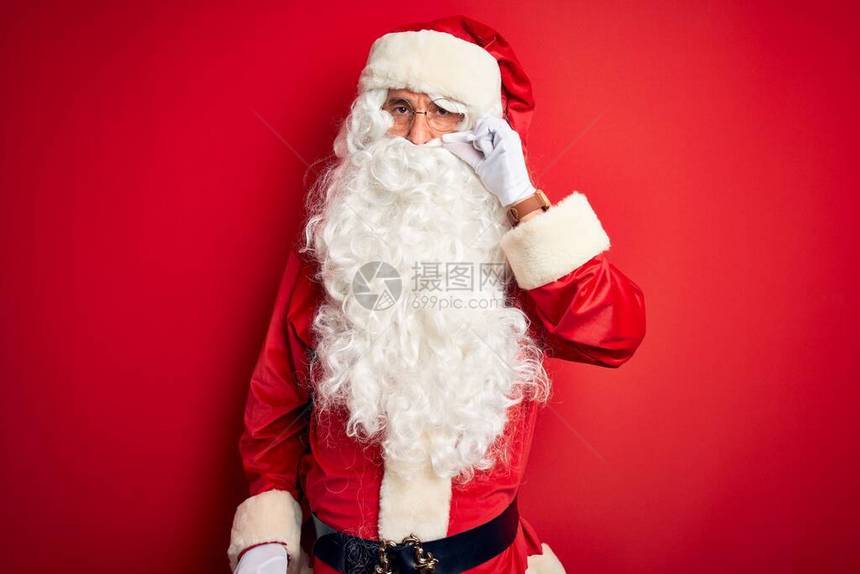 身着圣诞老人服装的中年英俊男子站在孤立的红色背景嘴唇和嘴唇上图片