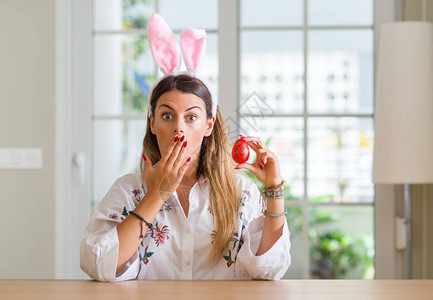 家中身穿复活兔子耳朵的年轻妇女用手顶住嘴部图片