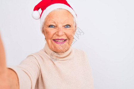 戴着圣诞帽的灰发女人在孤立的白色背景上自拍图片