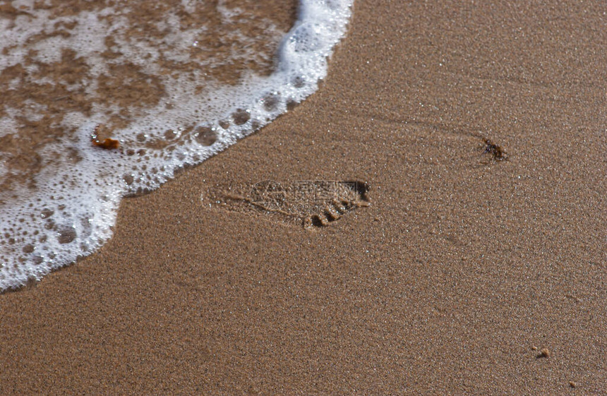 潮湿沙滩上的脚印水在冲洗图片