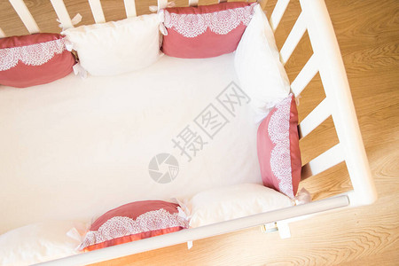 带有白色和勃伦顿色枕头的婴儿床带蕾丝图片