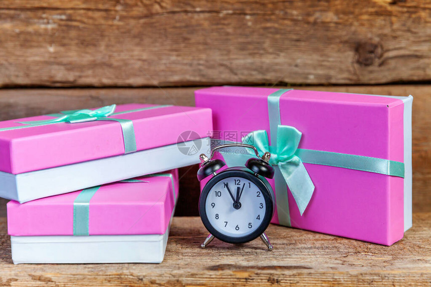 闹钟和礼品盒包裹着粉红色的纸圣诞节或新年装饰旧破仿古木制背景上的礼物圣诞节生日情人节庆祝浪漫礼图片