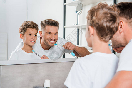 快乐的孩子和快乐的父亲在浴室刷牙时的图片