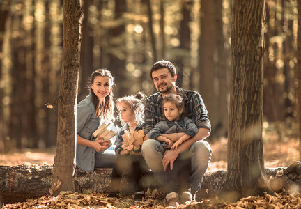 一个年轻美丽的家庭带着两个女儿在秋天的森林里散步家庭价值观图片
