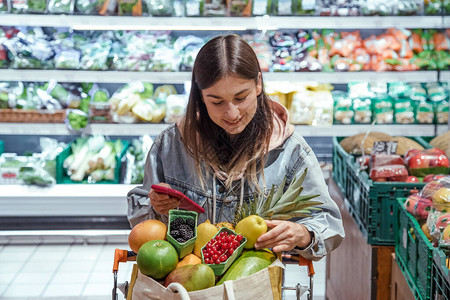 年轻女在超市用手机购买杂货健康食品图片