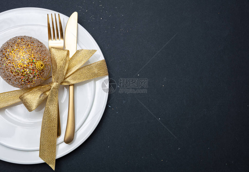 圣诞餐桌设置金餐具和白色盘子黑色背景图片