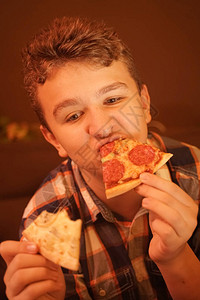 少年男孩吃比萨饼并享受它关闭图片
