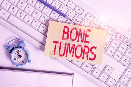 概念手写显示骨肿瘤概念意义可以是在骨骼中发现的良或恶生长平面位于pc键盘铅笔和时钟上的图片