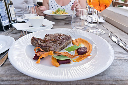 餐厅桌上白盘上的蔬菜用安格斯牛肉烹制的中度烤新鲜牛排图片