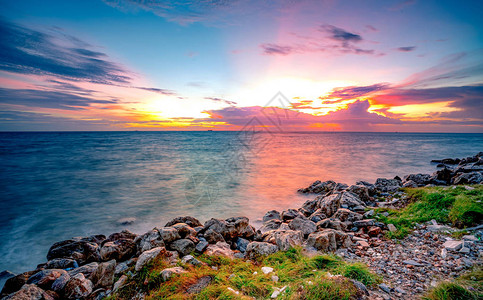 日落时在石滩上的岩石平静的海面美丽的风景黄昏的热带海戏剧多彩日落天空和云彩自然之美宁静祥和的概念干背景图片