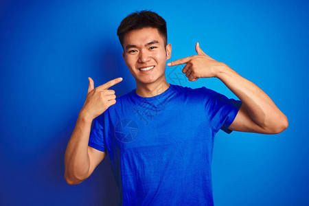 年轻的亚洲华人穿着T恤站在孤立的蓝色背景上图片