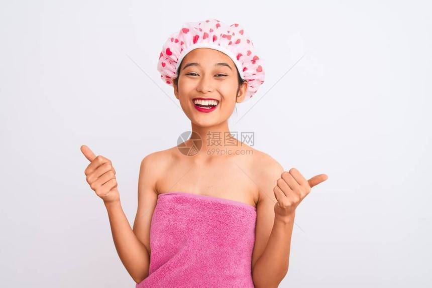 年轻妇女穿着浴巾和帽子浴缸图片