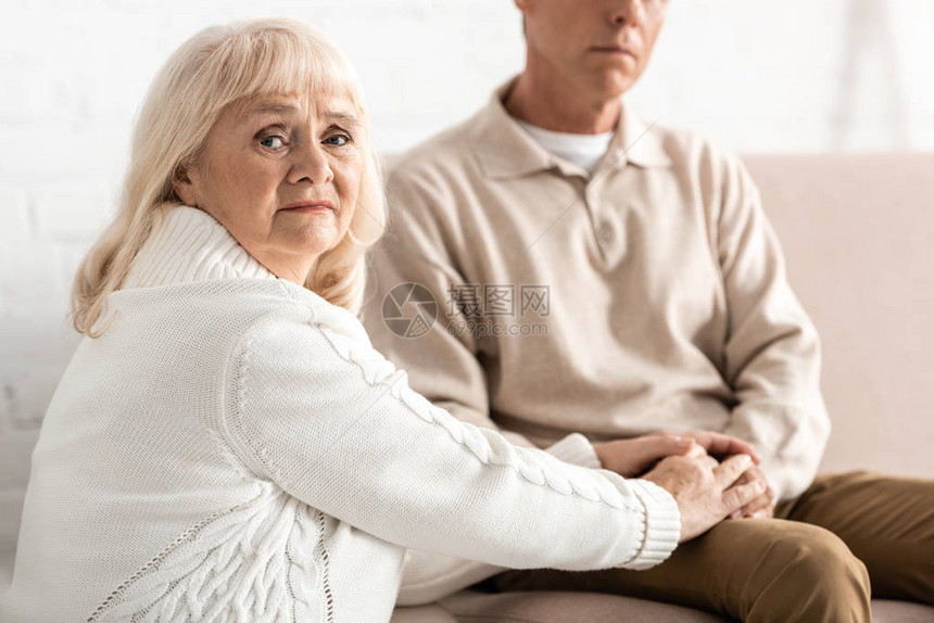 患有阿尔茨海默病的丈夫手中的悲伤的退休妇女有图片