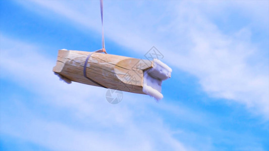 短木头挂在蓝云天空背景的建筑绳上图片
