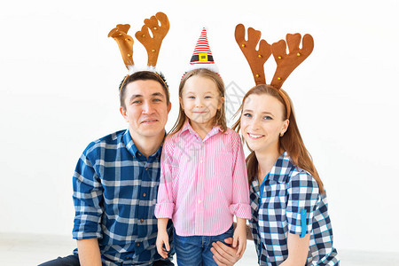 寒假概念戴着圣诞老人帽子和鹿角的圣诞家庭微笑的图片