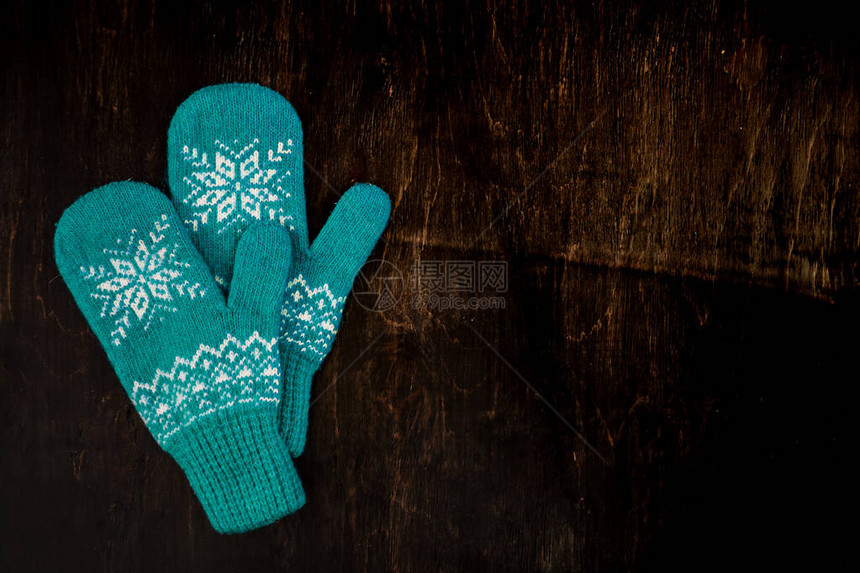 一对蓝色编织的手套印在深蓝绿褐色木质古董背景图片