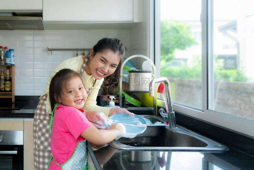 美丽的亚洲母女在家里厨房的水槽上用洗涤剂洗碗时玩得很开心快乐的家庭时光图片