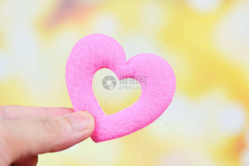 将粉红的心握在手中的人为情人节或捐赠帮助给爱温暖照顾图片
