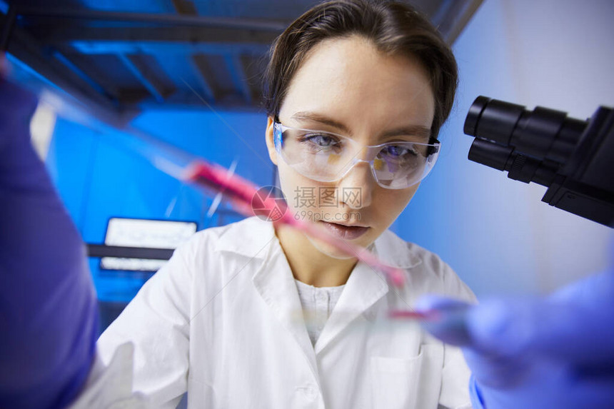 年轻女科学家在医疗实验室工作时使用滴水器进行测试样本图片