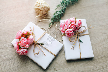 纸上包着玫瑰分枝的两盒手制装在白纸上的便携礼物盒图片