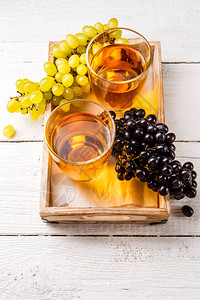 两杯红酒黑葡萄和绿葡萄放在桌上的图片