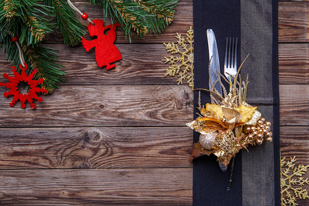 圣诞餐桌位布置用叉子和刀子金花和雪花以及圣诞松树枝装饰黑色餐巾图片