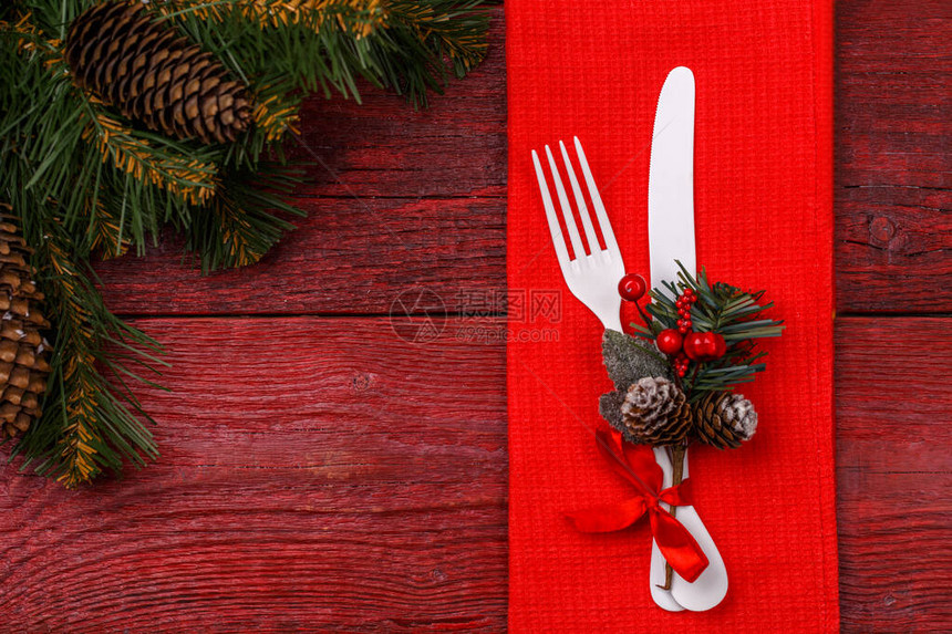 与红色餐巾白色叉子和刀子槲寄生和圣诞松树枝装饰的圣诞桌餐位具图片