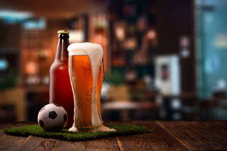 酒吧柜台绿草上的足球杯子和啤酒图片