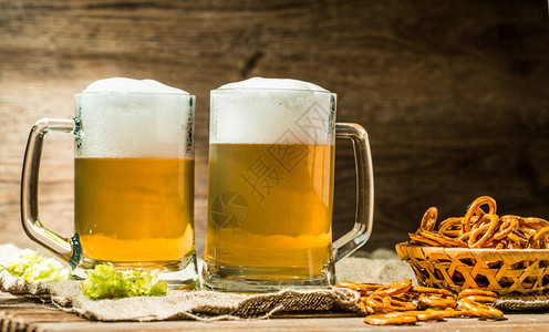 两杯啤酒杯在木桌布上图片