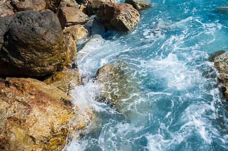 蓝色的波浪在岸边的岩石上破碎图片