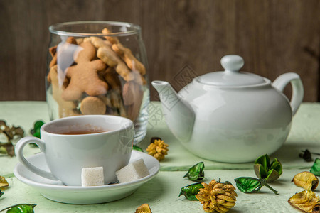 绿桌上的白茶壶和茶杯装饰干花图片