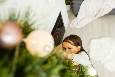 可爱的小女孩躺在圣诞树下在圣诞节前夕一个壁炉旁图片