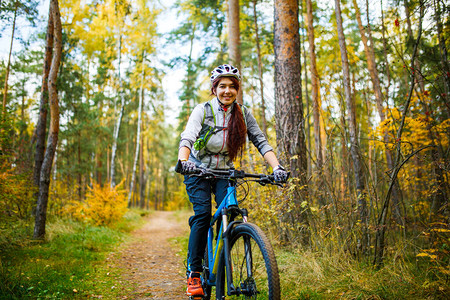 在秋森林骑自行车的女孩身图片