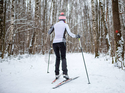 冬季森林中穿着白色夹克的女滑雪者照片图片