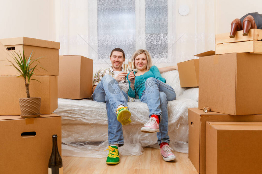 照片一对夫妇坐在沙发上和在新公寓的纸板图片