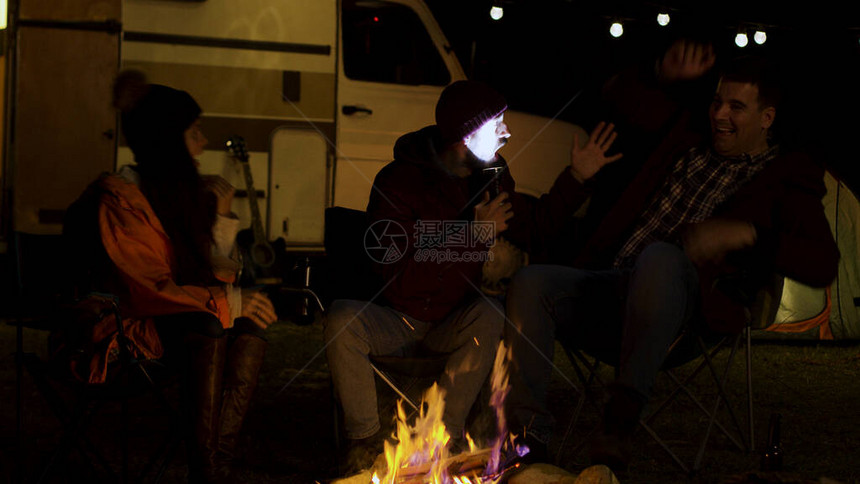 在秋天寒冷的夜晚胡子人给营地火灾周围的朋友讲一个可怕的故事Retro露营图片