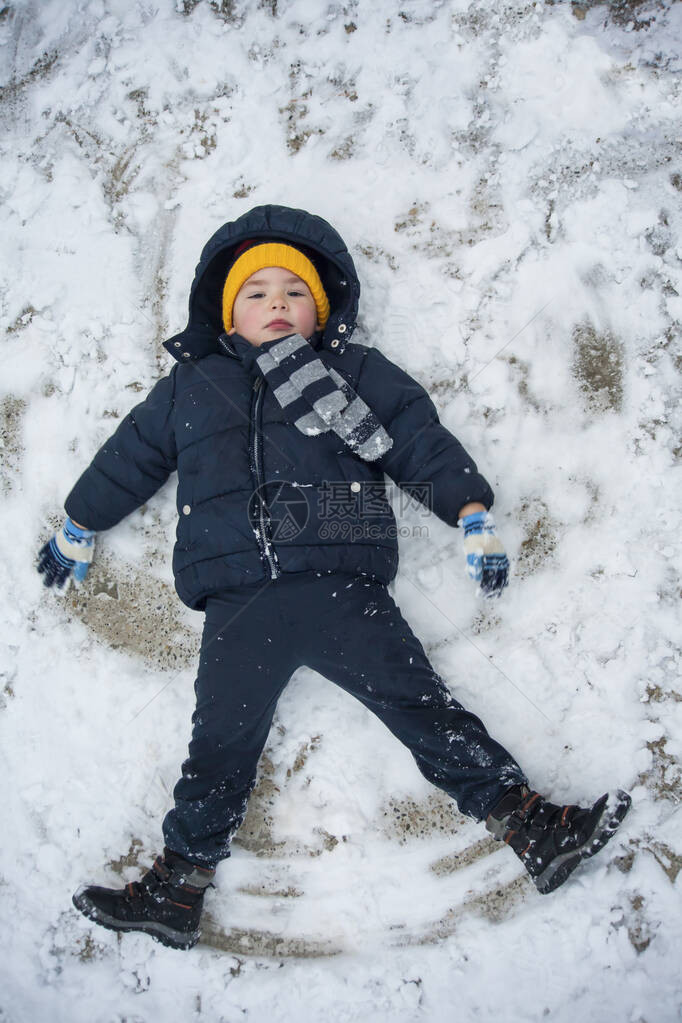 穿着蓝色夹克和蓝色裤子的男孩躺在雪地里图片