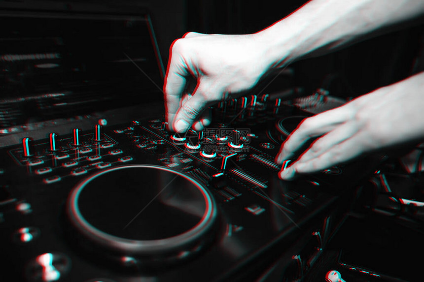 DJ控制器的手在用于混合音乐的专业混音器上进行音乐具有故障效果和小颗图片