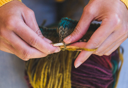女手特写年轻女子正在编织针织和线多色纱线编织者的手爱好对图片