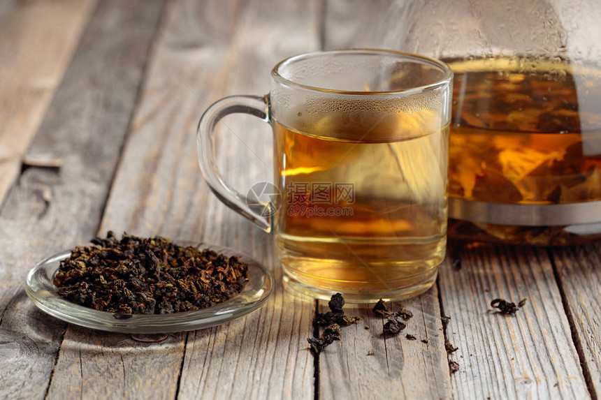 杯子里的热绿茶干茶叶和热饮放在木制桌子图片